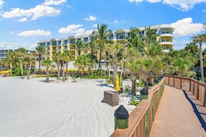 A resort with a sandy beach, palm trees, and a wooden boardwalk leading to a building with multiple balconies. - The Residences on Siesta Key within Hyatt Residence Club (Siesta Key)