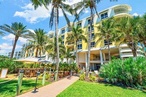 A multi-story hotel with a yellow facade, palm trees, and a covered outdoor seating area. - The Residences on Siesta Key within Hyatt Residence Club (Siesta Key)