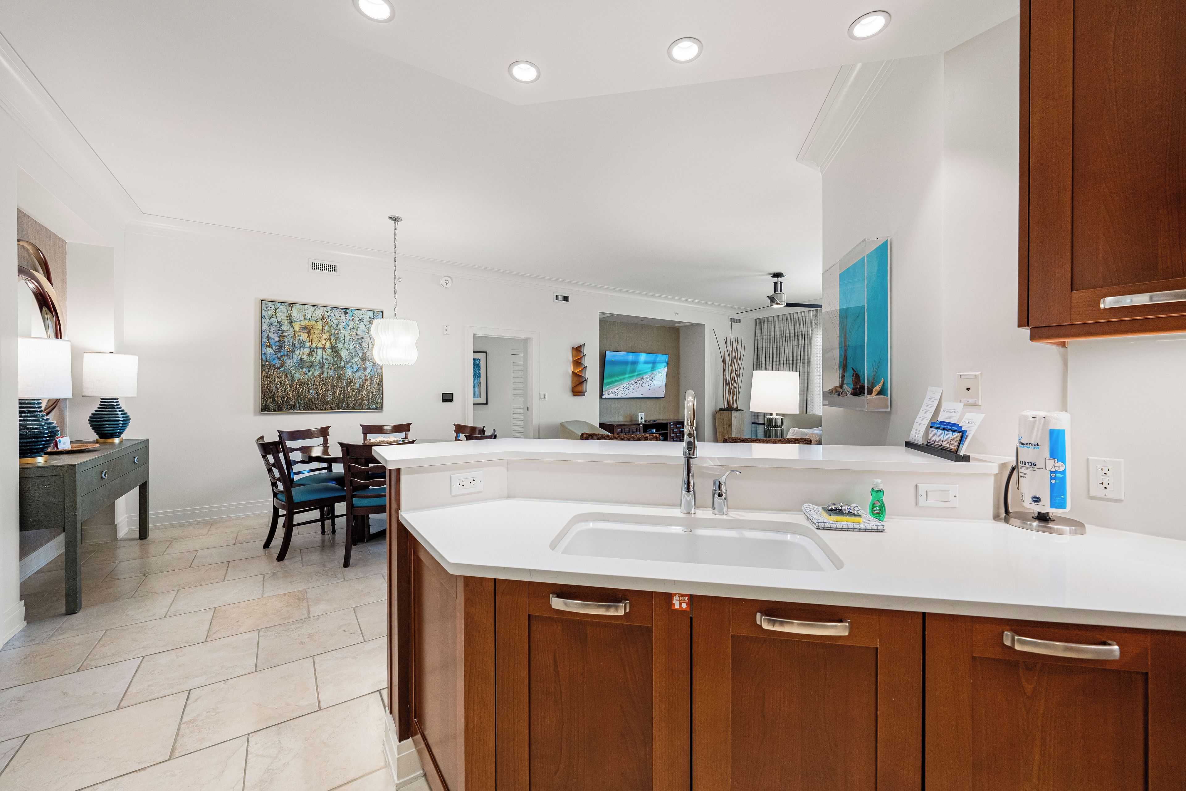 A modern kitchen with a large island, white countertops, and wooden cabinets.