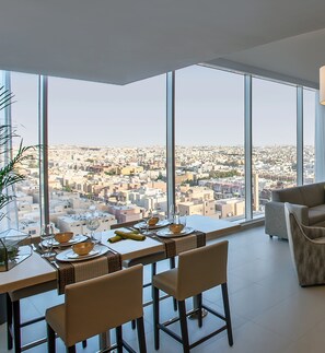 A dining area with a panoramic city view, a high ceiling, and modern furnishings. - Ascott Rafal Olaya Riyadh (Riyadh)