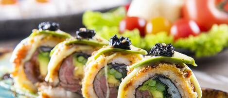 A sushi dish with various ingredients and a green sauce.