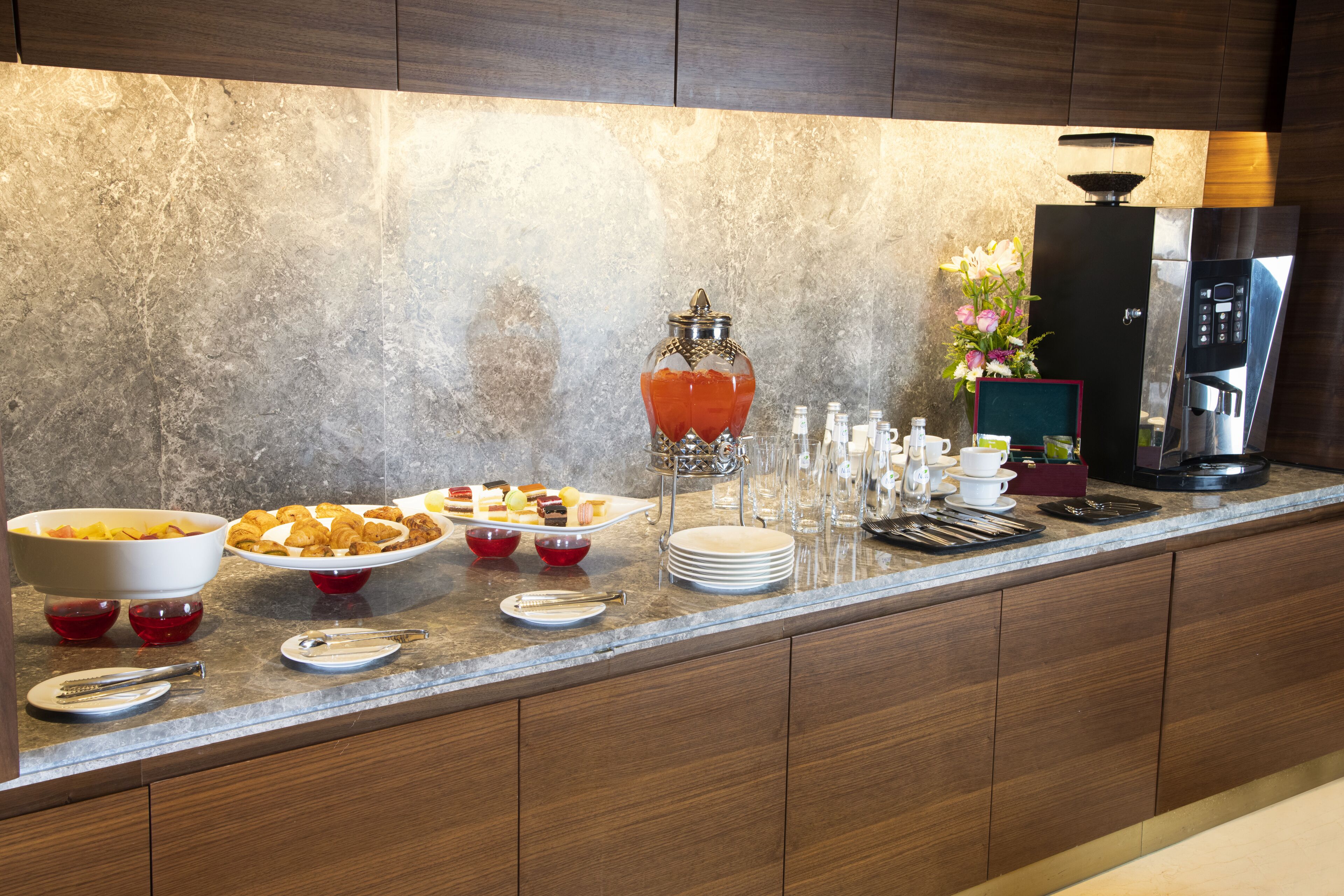 A buffet setup with various food items, a coffee station, and a decorative vase.