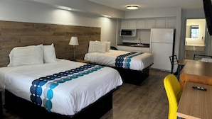 Habitación de hotel con dos camas, un escritorio, una silla, microondas, refrigerador y lavabo.