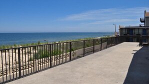 Vista de la playa con un paseo de hormigón y una valla de metal.