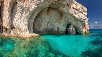 Formação rochosa natural com entrada de caverna e água turquesa translúcida.
