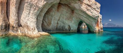 A natural rock formation with a cave entrance and clear turquoise water.
