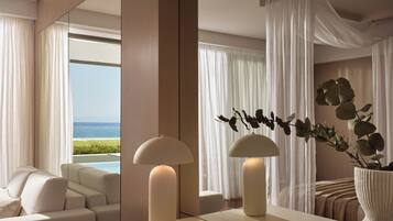 Habitación de hotel moderna con un espejo grande que refleja una vista a la playa, un sofá y un jarrón con plantas.