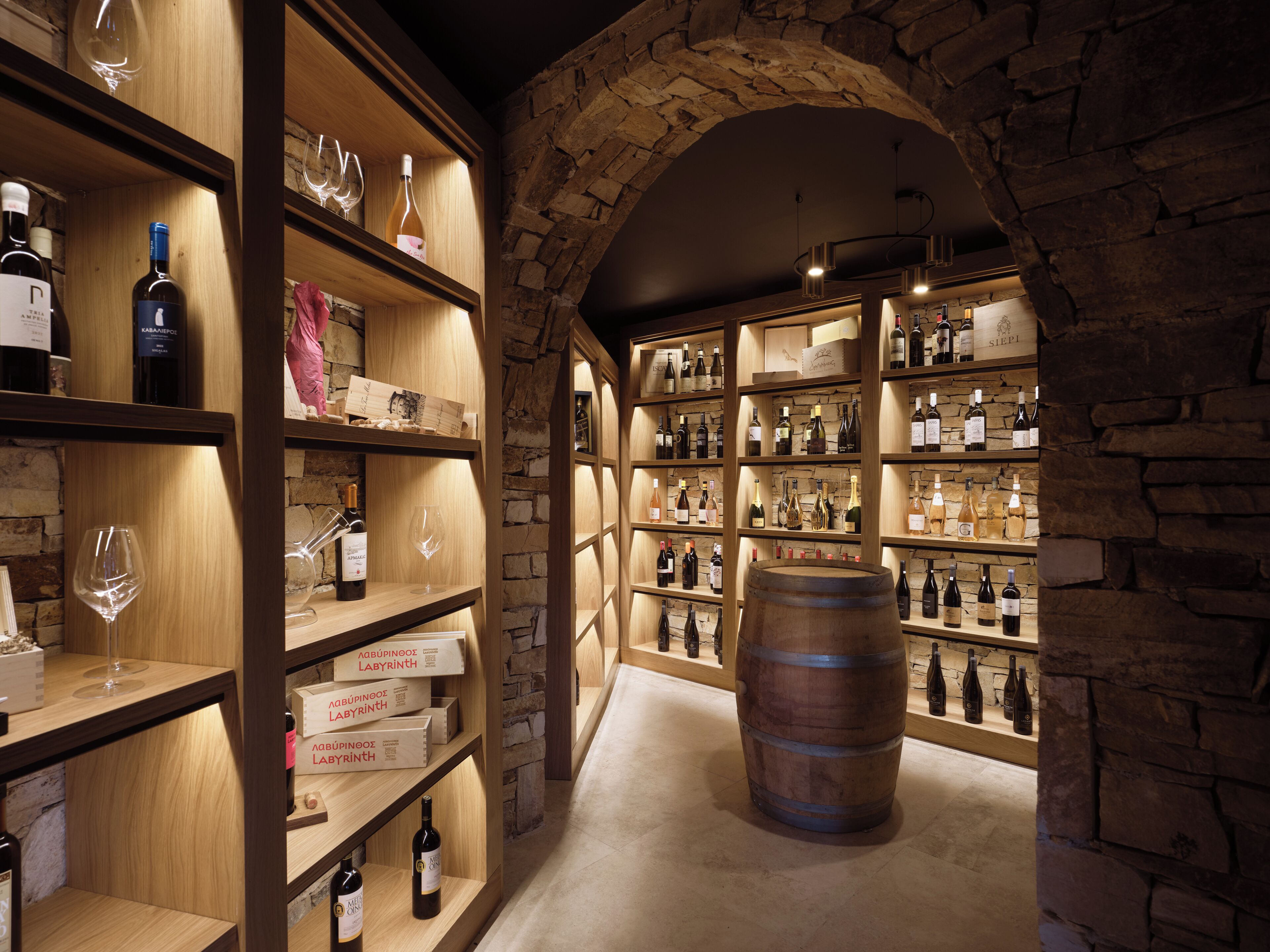 A wine cellar with wooden shelves and a stone archway.