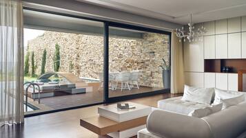 Un salón moderno con sofá, mesa de centro y vistas a un patio exterior con piscina y pared de piedra.