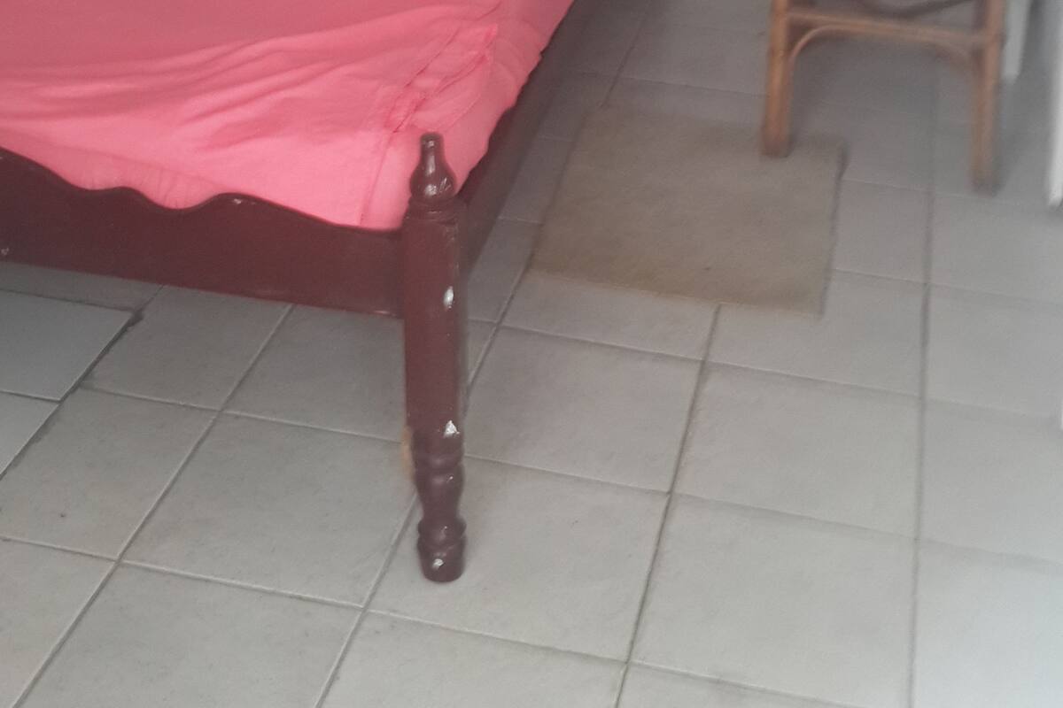 A bedroom with a wooden bed, a nightstand, and a tiled floor.