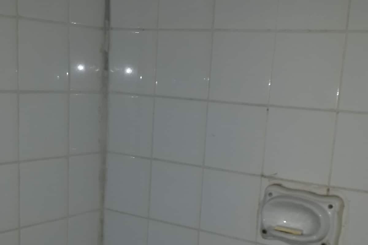 A tiled shower wall with a small, rectangular, white fixture.