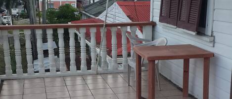 A balcony with tiled flooring, a wooden table, and a white railing.