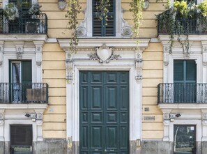 A building facade with a large green door, ornate architectural details, and balconies with plants. - LHP Suite Piazza del Popolo (Rome)