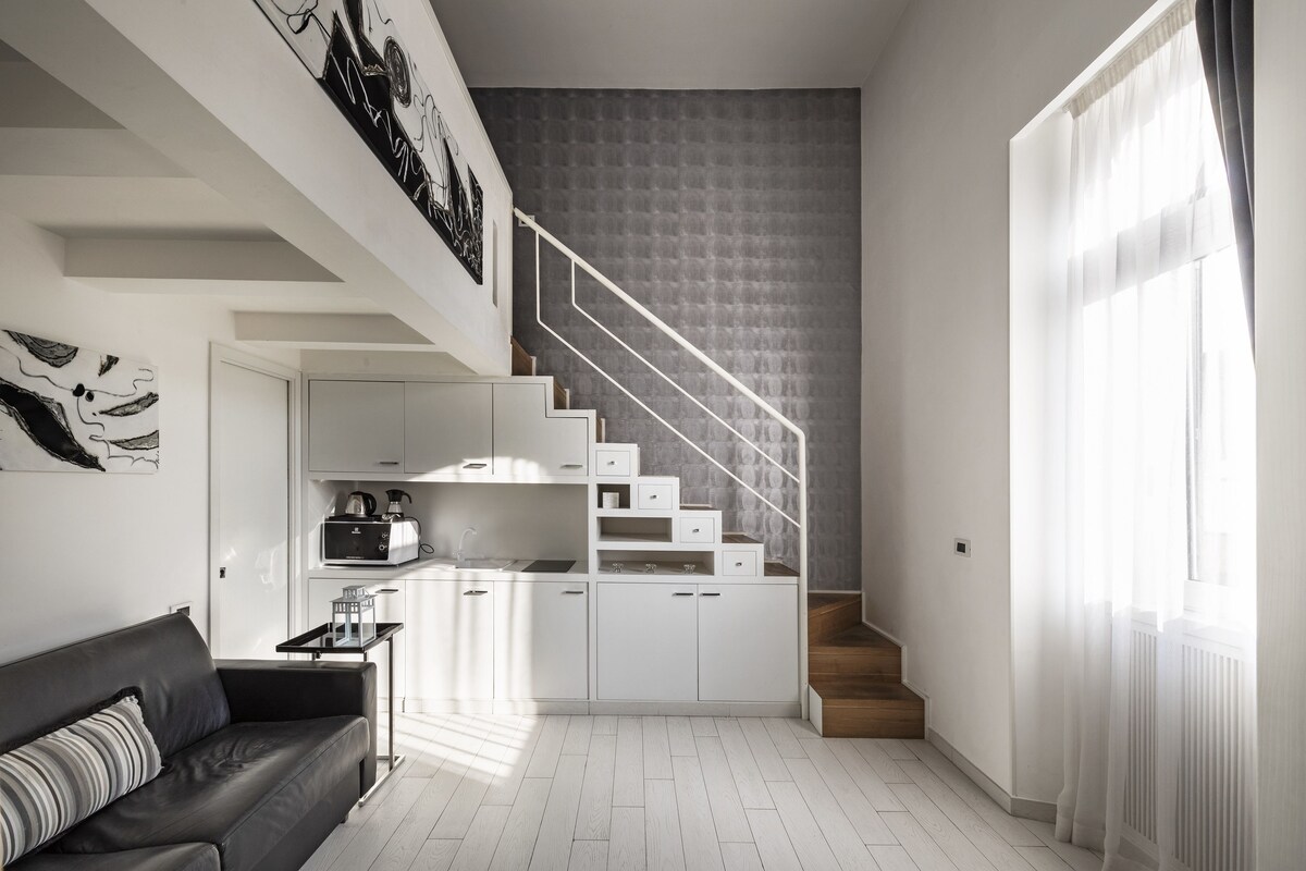 A modern apartment with a kitchen, a staircase, and a living area.