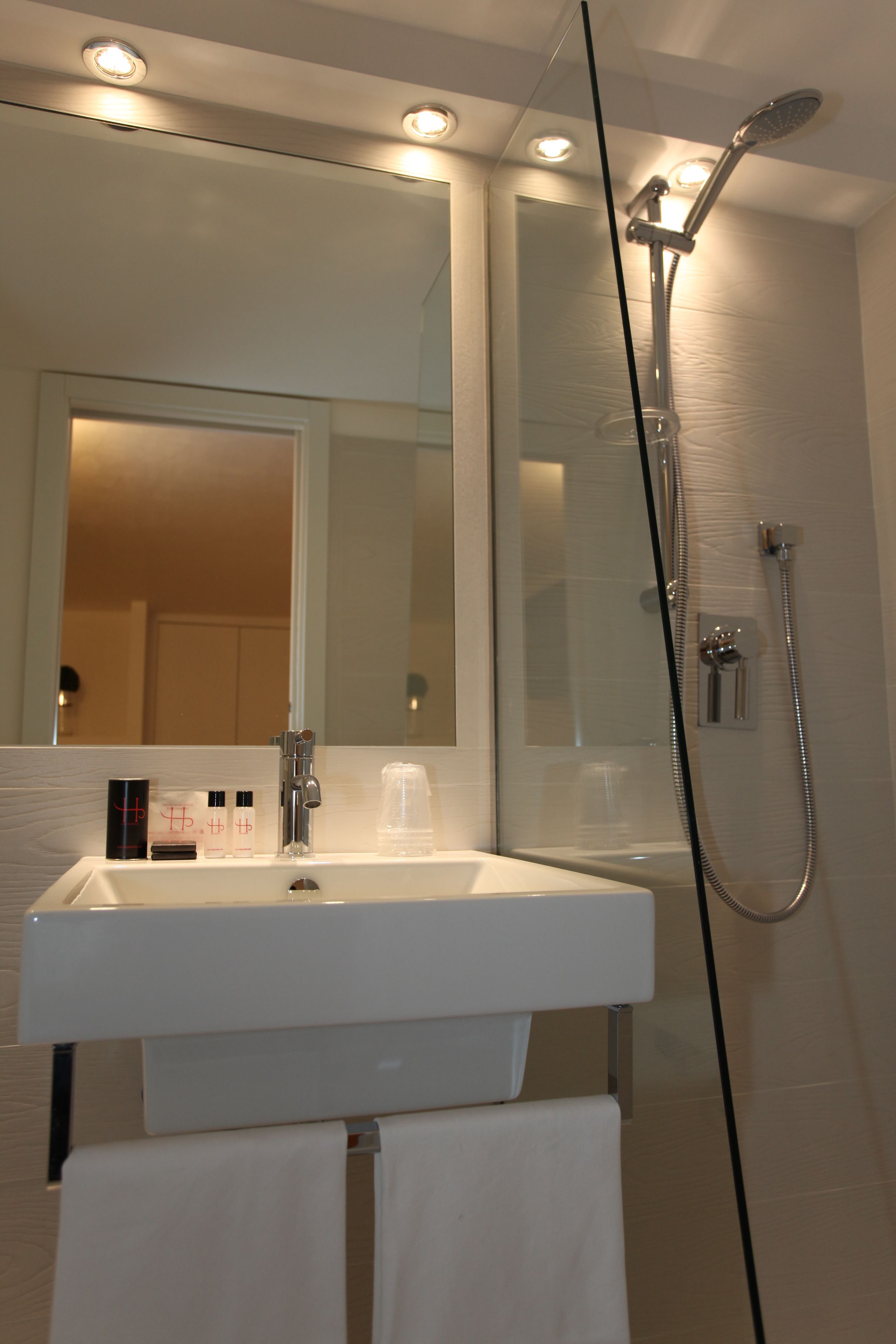 A modern bathroom with a white sink, mirror, and glass-enclosed shower.