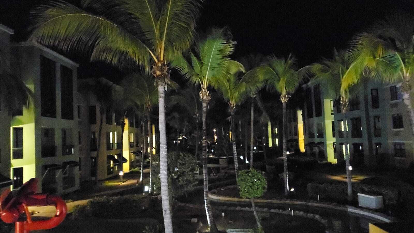 Nachtsicht eines Resorts mit Palmen und modernen Gebäuden.