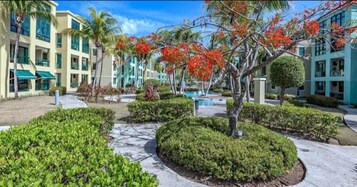 Un resort con piscina, palmeras y un jardín bien cuidado.