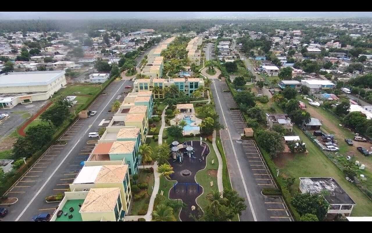 Zona residencial con una calle central, espacios verdes y edificios con tejados de diferentes colores.