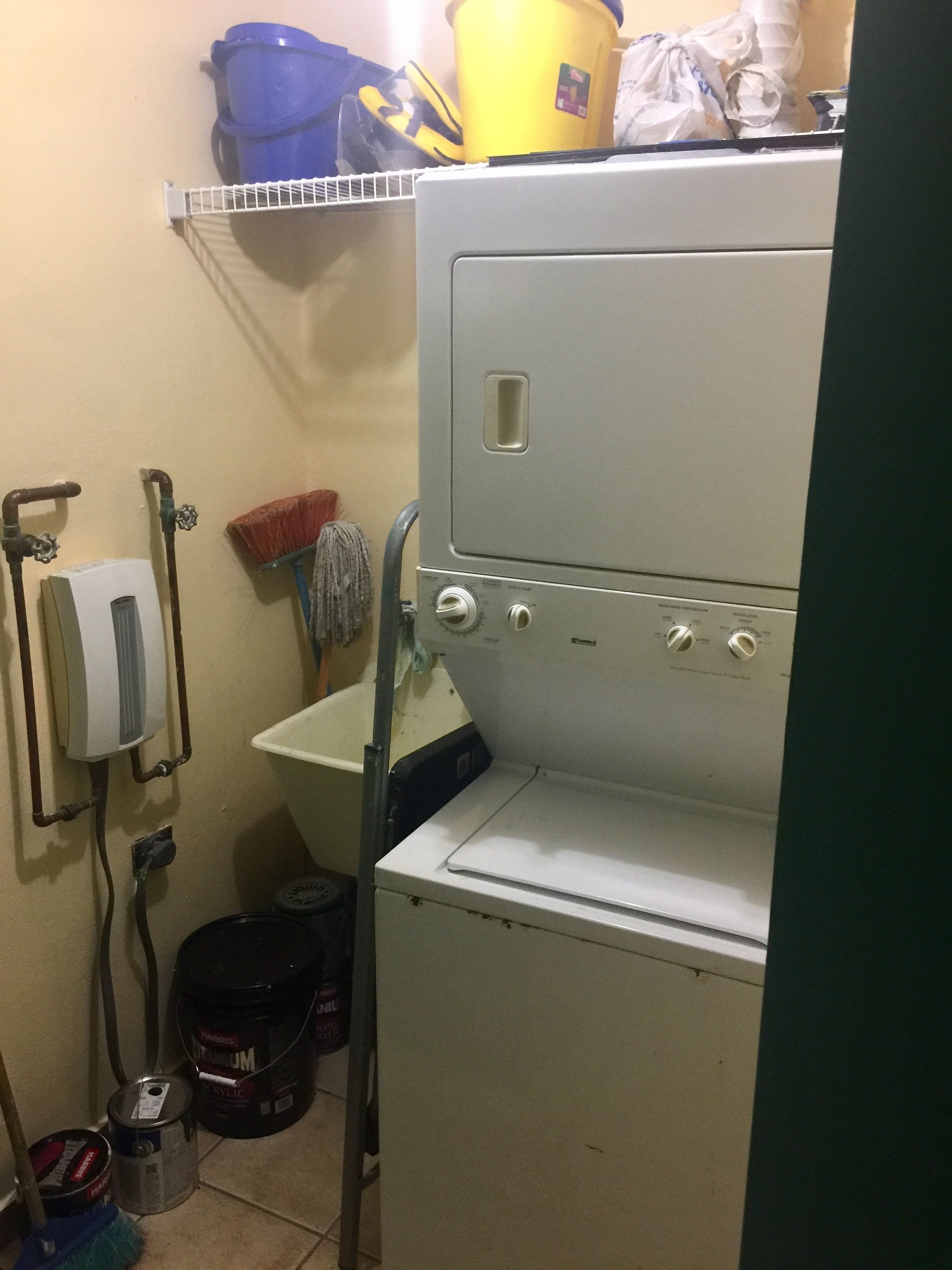 A compact laundry area with a washing machine, a sink, and a mop.