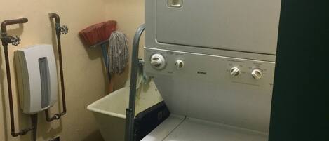 A compact laundry area with a washing machine, a sink, and a mop.