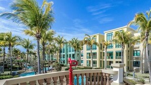 Un hotel con edificios de varios pisos, piscina y palmeras.
