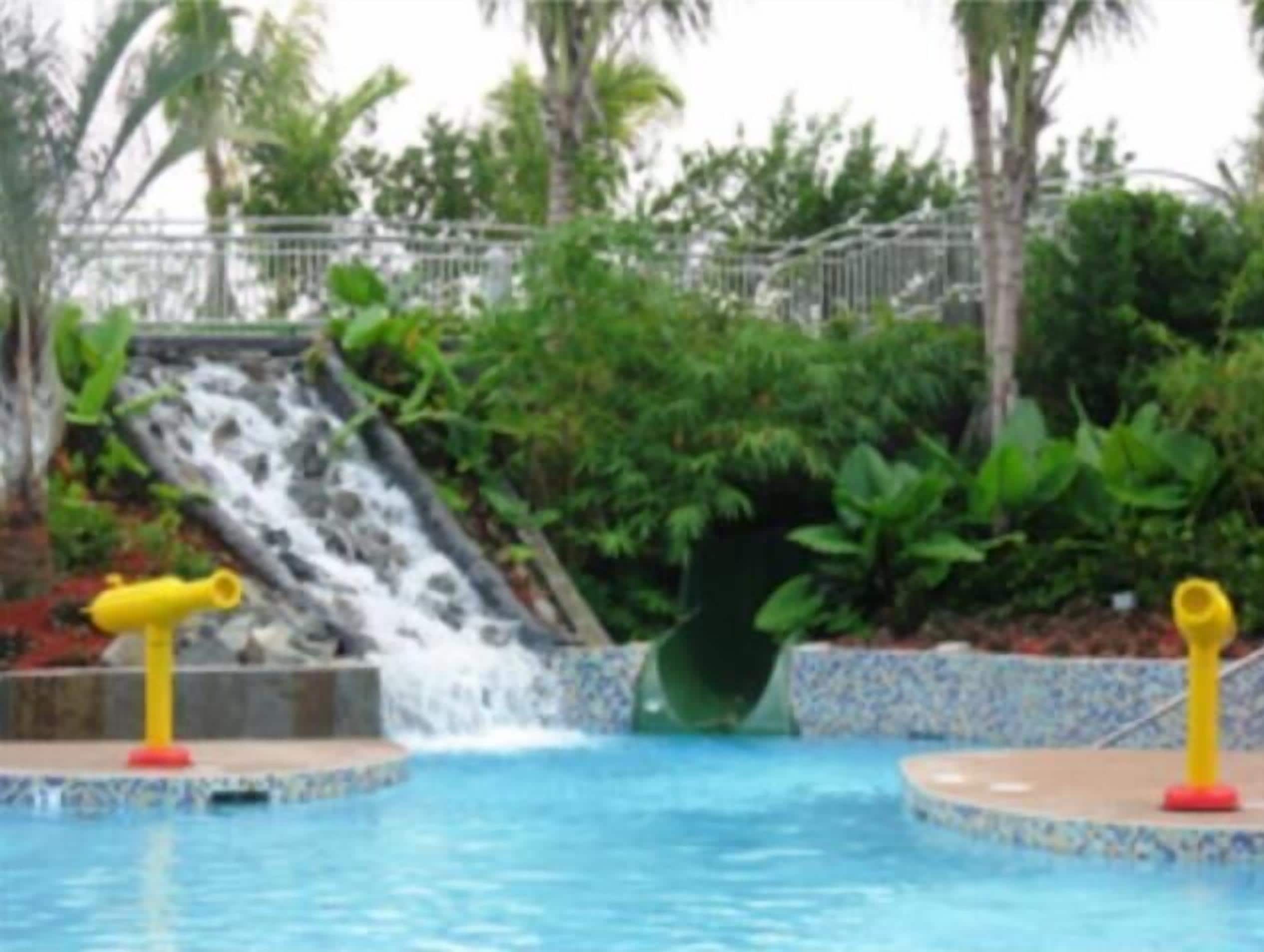 A pool with a water slide and two yellow water cannons.