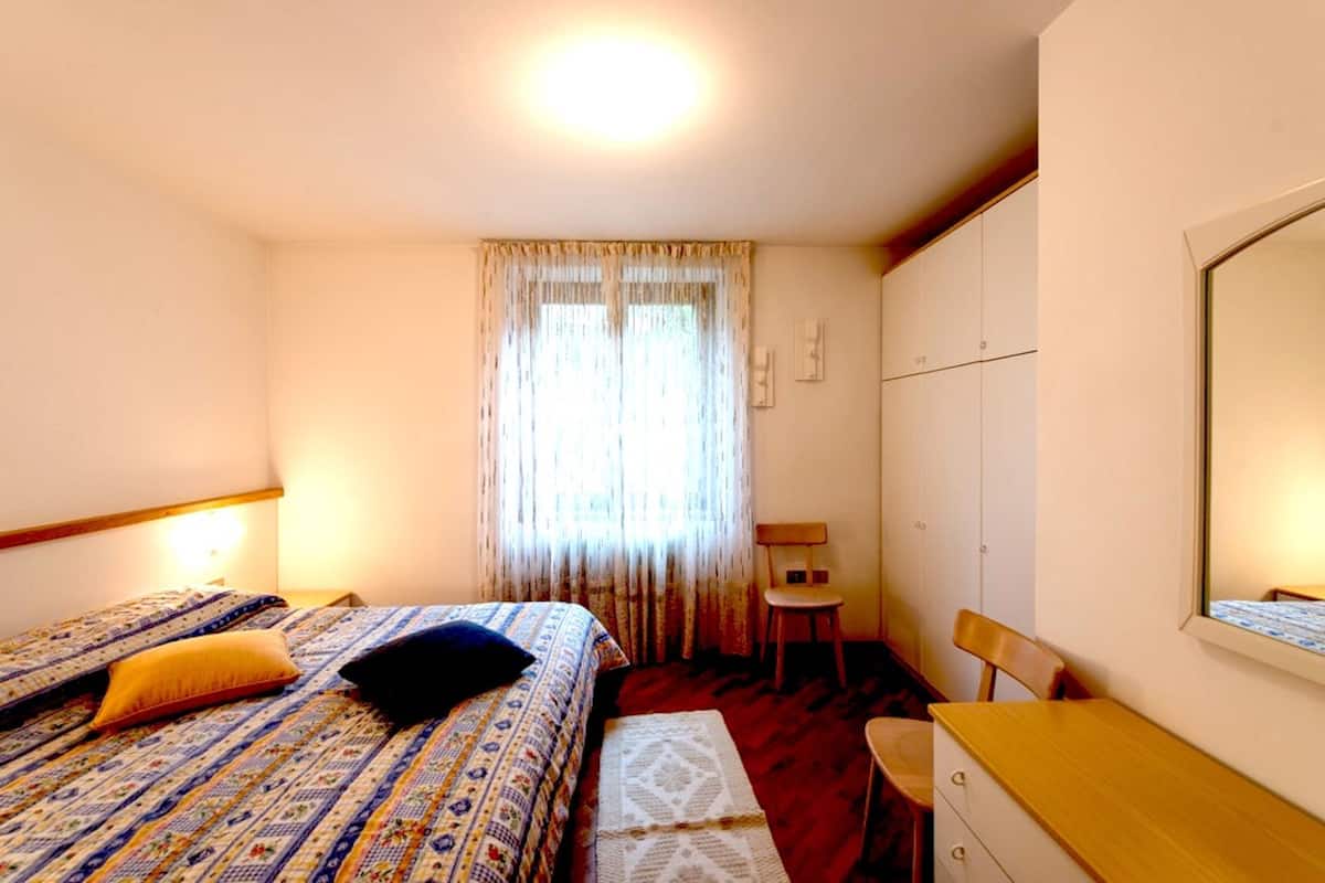 Ein Schlafzimmer mit Bett, Stuhl, Schreibtisch und Kleiderschrank.