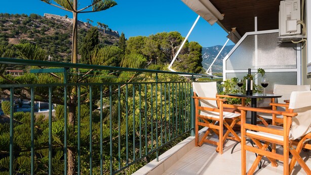 Un balcon avec vue sur un paysage montagneux, une table avec des chaises et un appareil de climatisation.