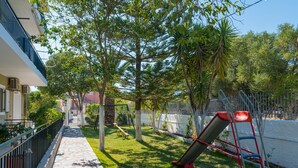 Un quartier résidentiel doté d’un chemin piétonnier dallé, d’une aire de jeux avec un toboggan et d’une clôture.