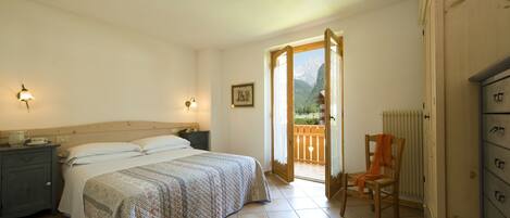 A bedroom with a bed, bedside tables, a chair, a dresser, and a view of the outdoors.
