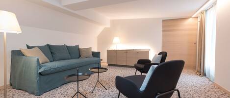 Una sala de estar moderna con un sofá, dos sillones, una mesita de centro y una lámpara.