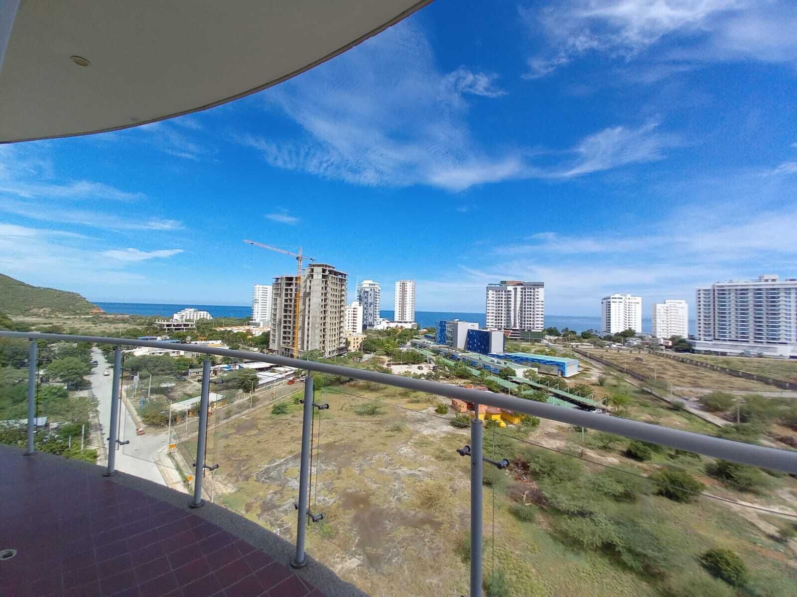 A balcony with a view of a coastal cityscape, including high-rise buildings and a construction crane.