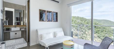 Une chambre moderne comprenant un lit, une chaise, une petite table et une grande fenêtre donnant sur l’extérieur.