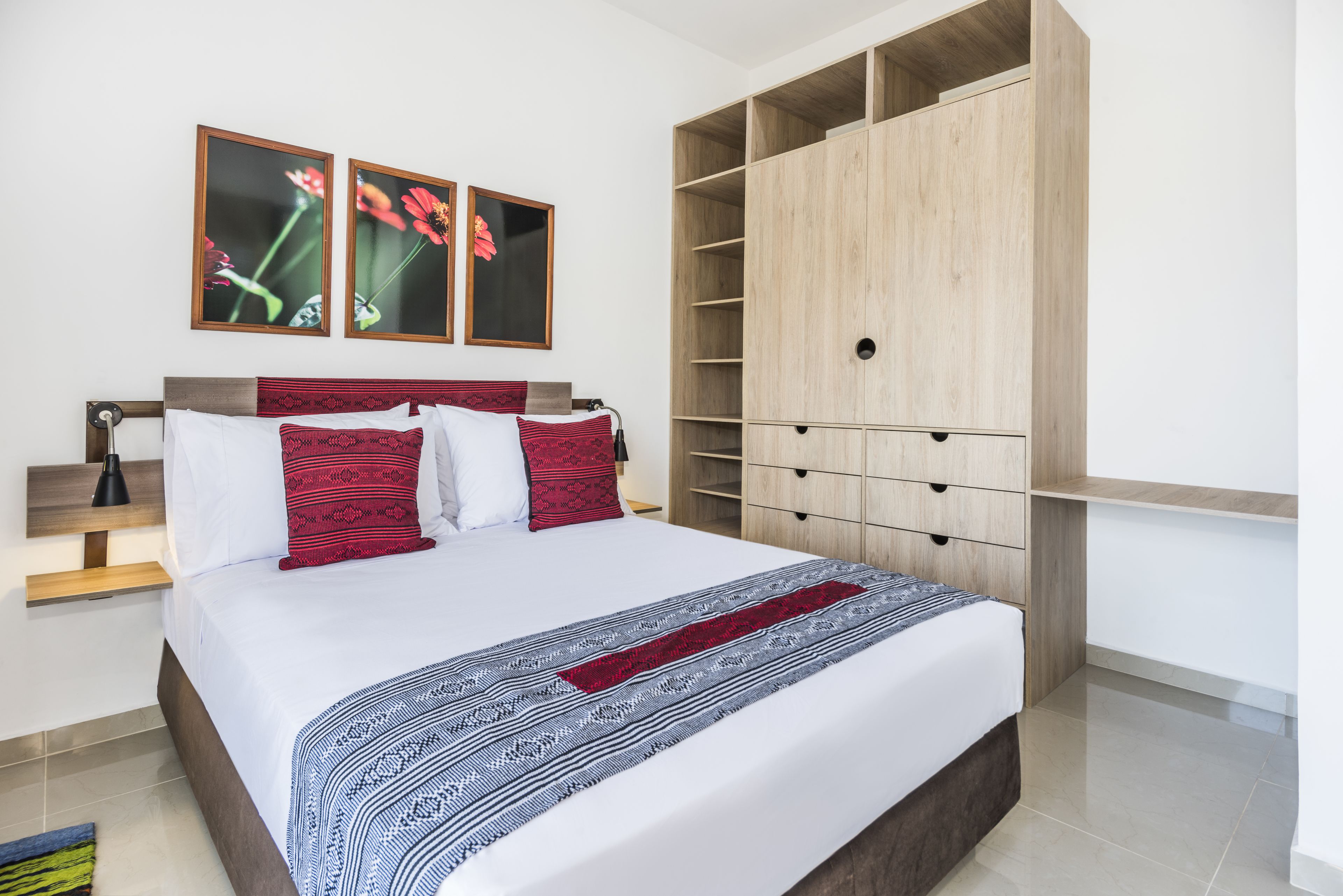 A modern bedroom with a large bed, wooden wardrobe, and two framed pictures on the wall.