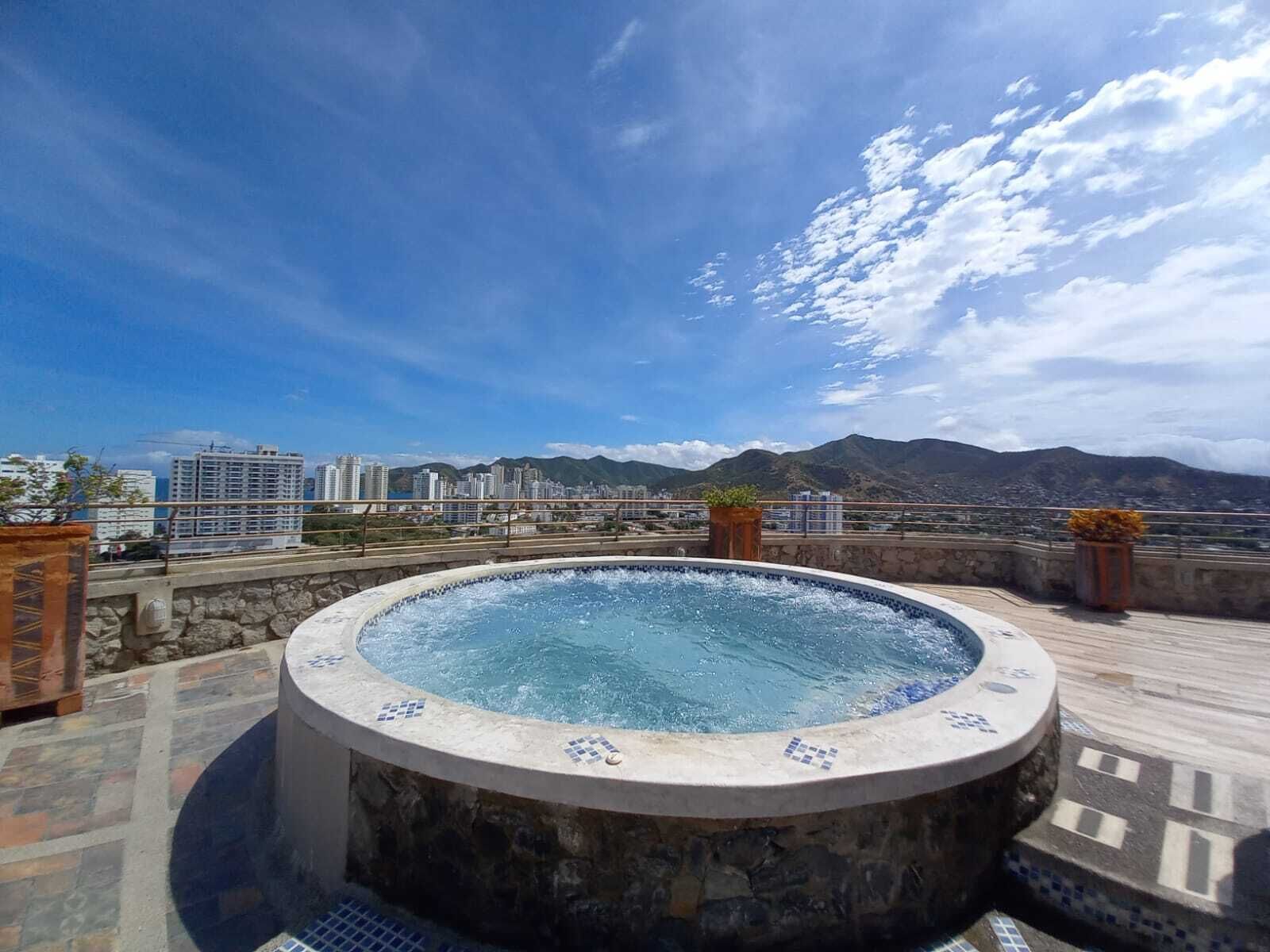 Een jacuzzi op een dak met een stadsgezicht en bergen op de achtergrond.