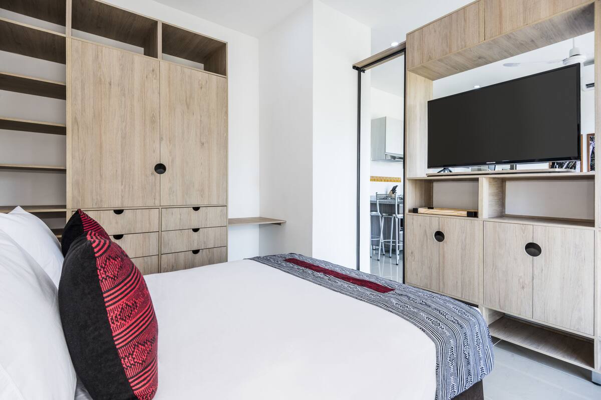 Un dormitorio moderno con cama, armario empotrado y televisión.