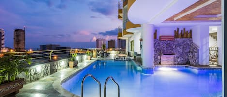 Een buitenzwembad, parasols bij het zwembad en ligstoelen