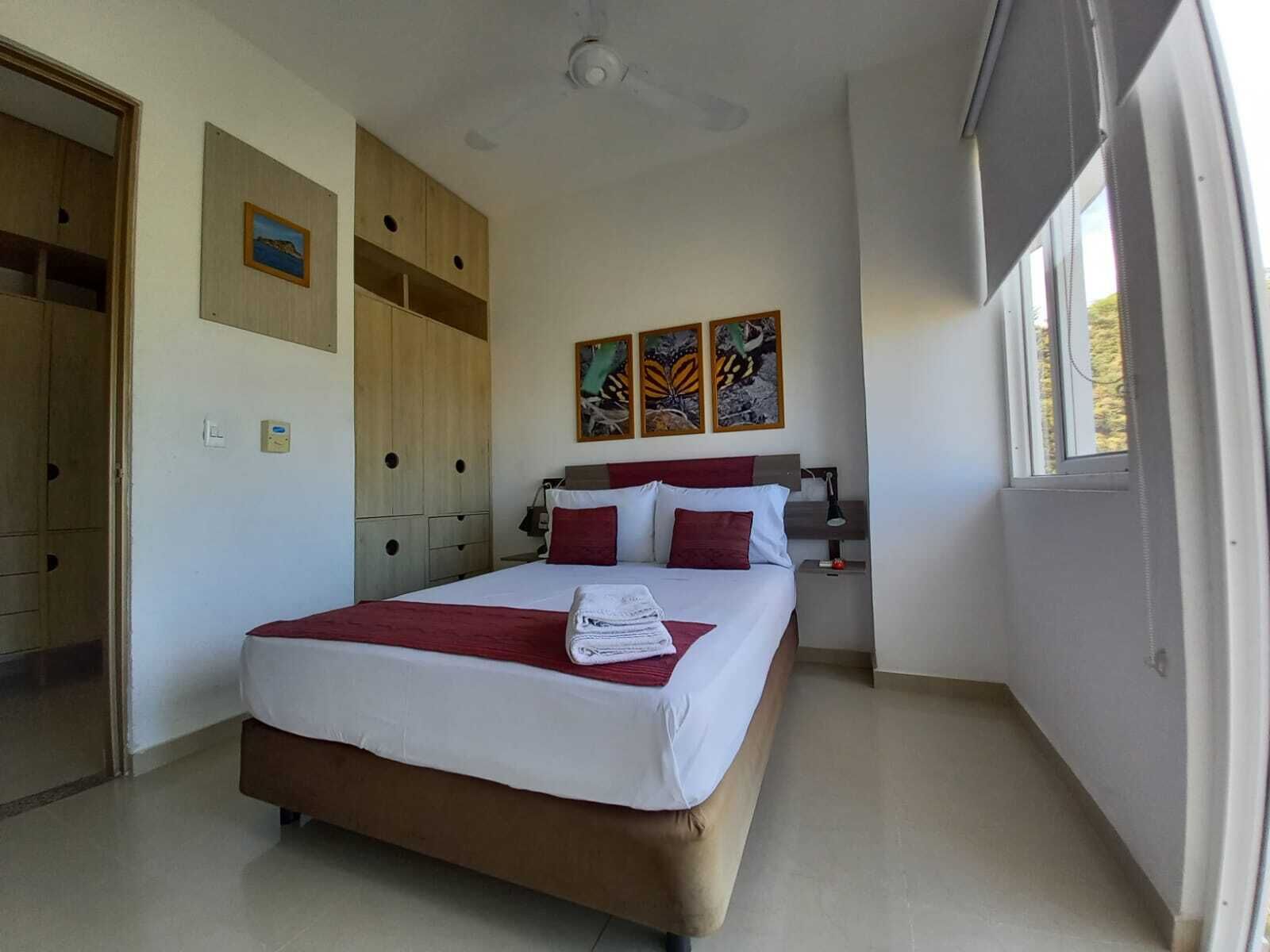 Une chambre à coucher avec un lit, une armoire, une table de chevet et une fenêtre.