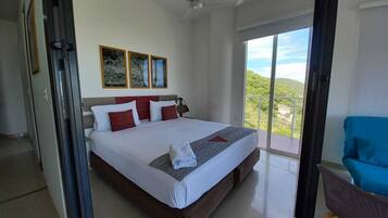 Un dormitorio moderno con una cama grande, un ventilador de techo y un balcón con vistas.