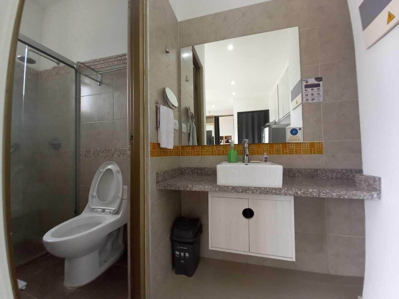 Un bagno con servizi igienici, lavandino, specchio e doccia.