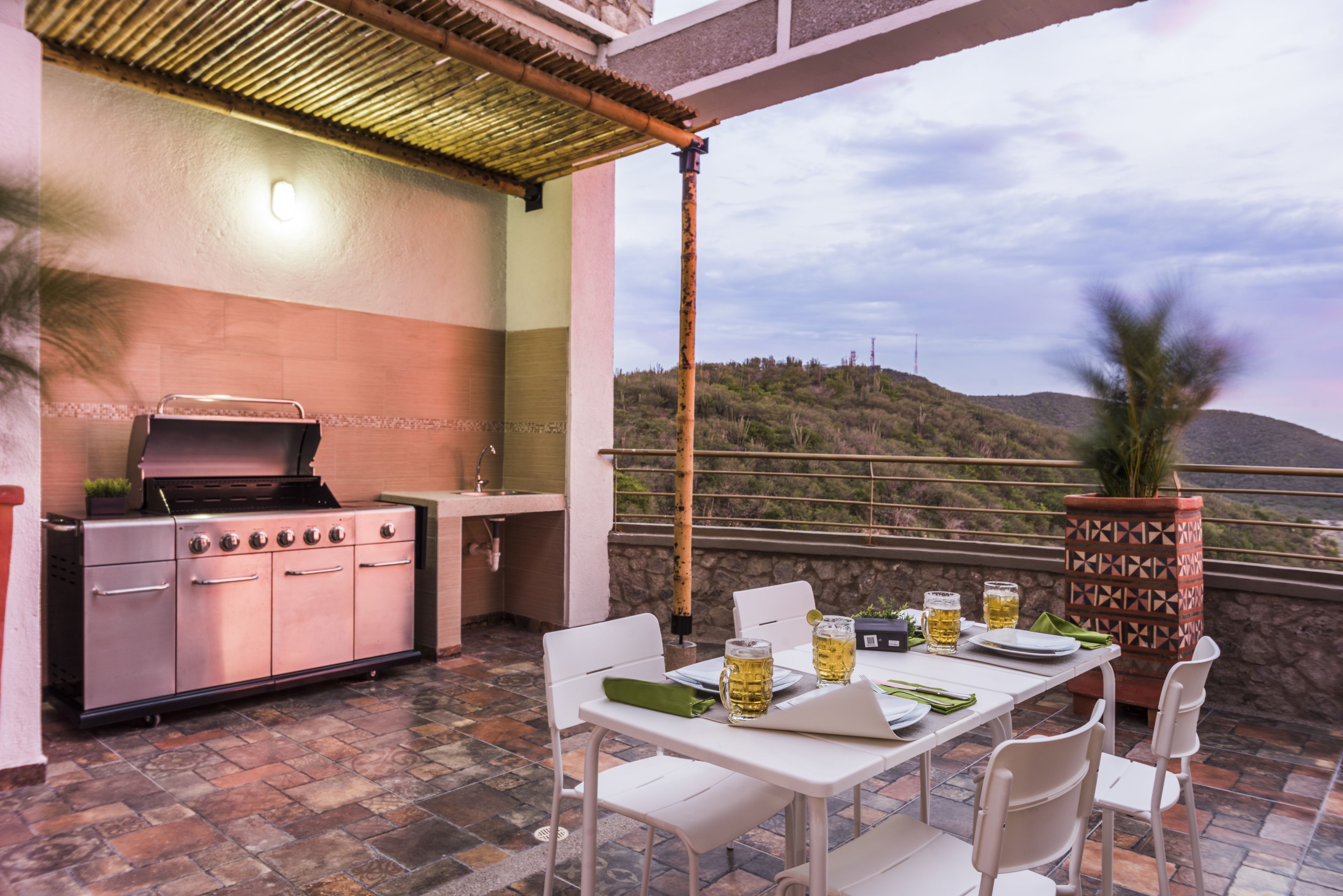 Un patio exterior con una parrilla, una mesa de comedor, sillas y una maceta decorativa.