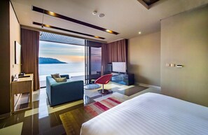 A modern hotel room with a large bed, a sofa, a TV, and a desk. - Impiana Private Villas (Phuket)