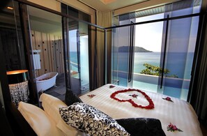 A hotel room with a large bed, a bathtub, and a view of the sea. - Impiana Private Villas (Phuket)