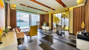 A modern hotel room with a large balcony, a sofa, a dining area, and a TV. - Impiana Private Villas (Phuket)