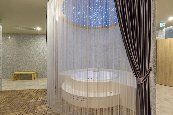 Um banheiro moderno com pia circular, um banco e uma cortina decorativa.