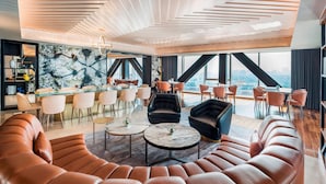 A modern lounge area with leather sofas, marble coffee tables, and a bar with high stools.
