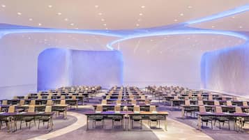 A conference room with rows of tables and chairs, a curved ceiling, and recessed lighting.