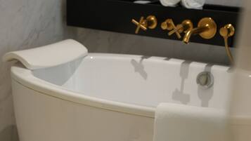 A modern bathroom with a freestanding bathtub, a gold faucet, and a towel rack.