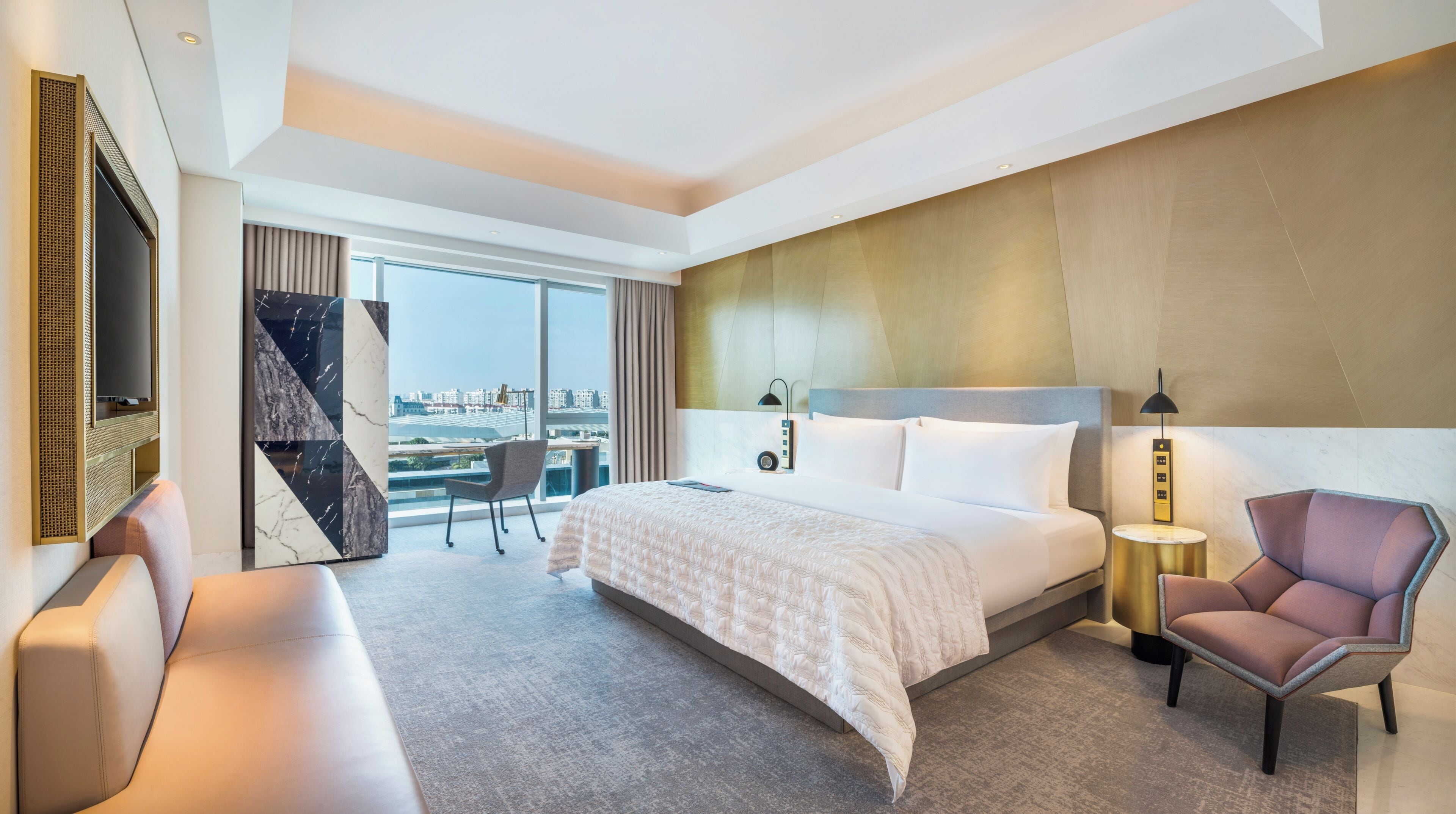 A hotel room with a large bed, a desk, a chair, and a TV.