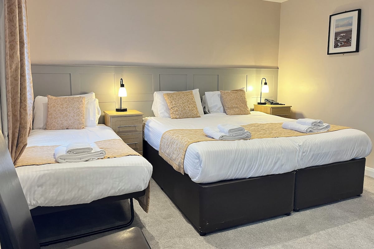 A hotel room with two beds, each with a bedside table and lamp, and a framed picture on the wall.